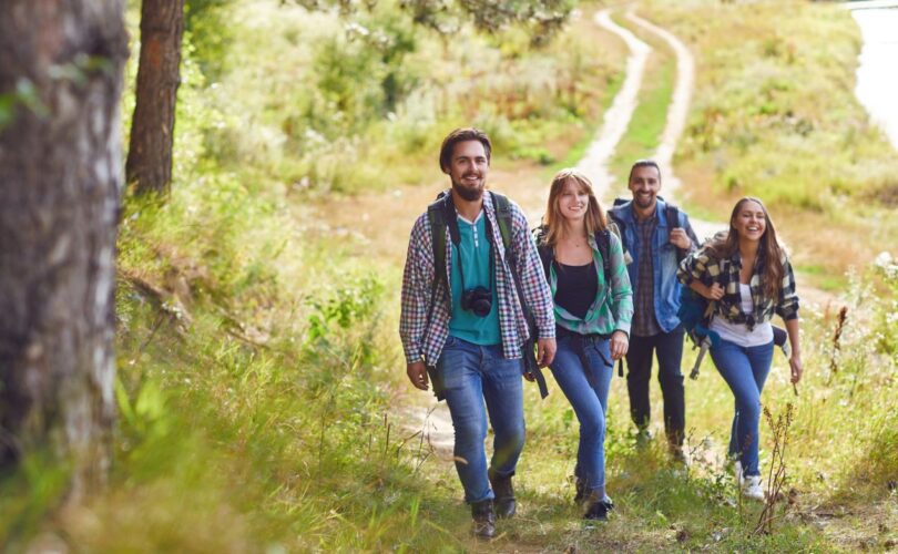 Vier junge Wanderer auf einem Naturpfad, die gemeinsam durch eine grüne Landschaft laufen – Vorbereitung auf die Besteigung Kilimandscharo